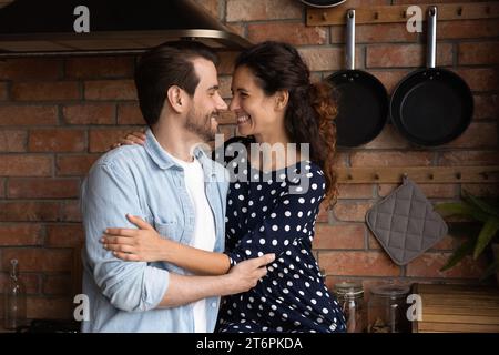 Heureux amoureux couple millénaire embrassant, profitant d'un moment romantique dans la cuisine Banque D'Images