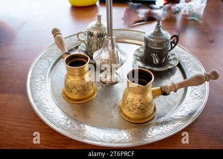 Café tunisien traditionnel, gros plan de tasse décorative ornementale en argent et or et soucoupe avec thé ou café Banque D'Images