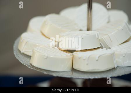 Ronds de macadamia couverts de glaçage vanille sur plateau à la réception de mariage du bar à desserts Banque D'Images