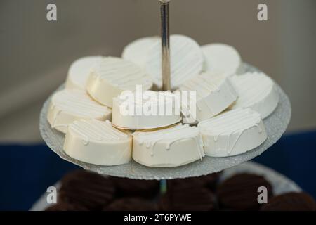 Ronds de macadamia couverts de glaçage vanille sur plateau à la réception de mariage du bar à desserts Banque D'Images