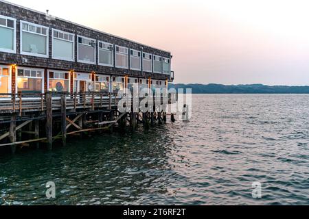 Un bâtiment à usage mixte d'entreprises et de restaurants s'avance dans les eaux du fleuve Columbia sur un quai au bord de l'eau d'Astoria, Oregon. Banque D'Images