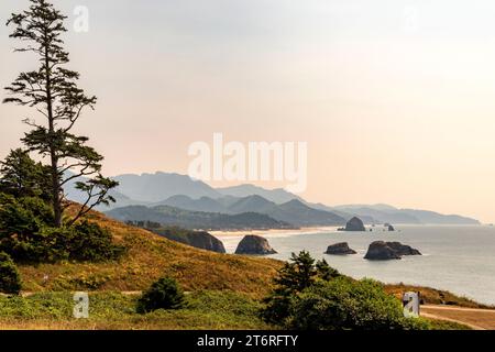 Une vue depuis Ecola State Park, Oregon, vers Cannon Beach avec l'emblématique Haystack Rock, et les collines accidentées de la côte de l'Oregon au-delà. Banque D'Images