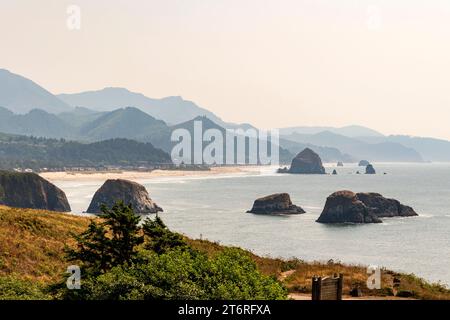 Une vue depuis Ecola State Park, Oregon, vers Cannon Beach avec l'emblématique Haystack Rock, et les collines accidentées de la côte de l'Oregon au-delà. Banque D'Images