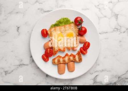 Mignon sandwich monstre avec tomates cerises, œufs au plat et saucisses sur table en marbre blanc, vue de dessus. En-cas Halloween Banque D'Images