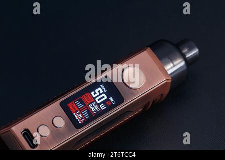 Un appareil électronique moderne avec un écran et des boutons pour vaporiser. Macro photo sur un fond sombre Banque D'Images