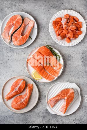 différents types de saumon cru sur fond gris dans une assiette - tranches, filets sur la peau, médaillons et steaks de saumon . Photo de haute qualité Banque D'Images