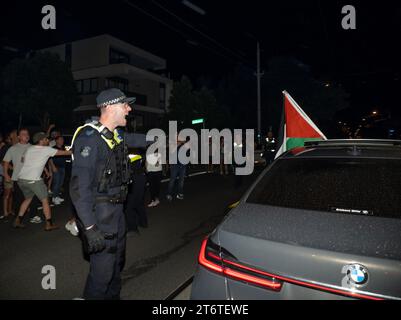 Un policier crie à un conducteur de déplacer sa voiture arborant un drapeau palestien alors qu'il s'arrête sur la route. Des contre-manifestants pro-israéliens empêchent un autre manifestant de s'approcher de la voiture après qu'un restaurant de la chaîne Burgertory appartenant à l'australien-palestinien Hesham Tayah ait brûlé pendant la nuit dans la banlieue la plus juive de Melbourne. Des manifestants pro-palestiniens se sont rassemblés dans un parc voisin où de violents échanges ont eu lieu avec des contre-manifestants pro-israéliens. La police a déployé du gaz poivré des deux côtés et a procédé à une arrestation. (Photo Alex Zucco / SOPA Images/Sipa USA) Banque D'Images