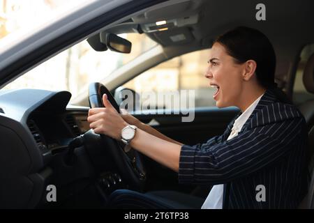 Une conductrice en colère criant dans sa voiture. Coincé dans un embouteillage Banque D'Images