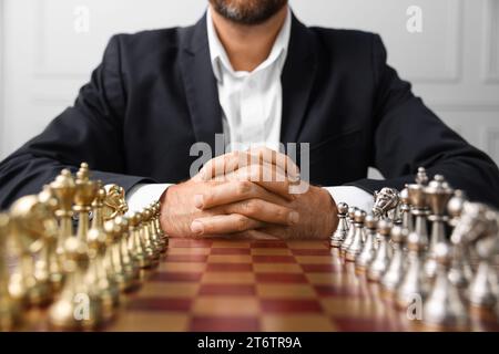 Homme avec des pièces d'échecs sur échiquier avant le match à l'intérieur, closeup Banque D'Images