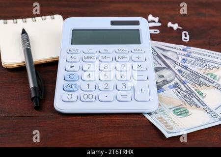 Calculatrice, cahier, stylo et billets de banque en dollars sur la table en bois. Concept de retraite Banque D'Images