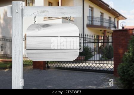 Signe en bois blanc vide près de belle maison à l'extérieur Banque D'Images