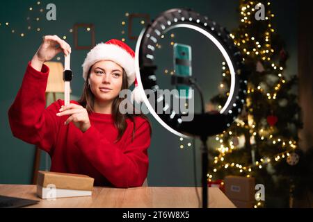Visualisation vidéo. Jeune femme caucasienne démontrant montre intelligente devant la caméra du smartphone, enregistrant du contenu pour son blog de mode, déballant la boîte Banque D'Images