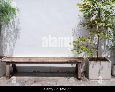 Vide vieux long banquette en bois avec personne sur un mur blanc près de la décoration des grands pots en béton à l'extérieur du bâtiment. Banque D'Images