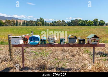 Tasmanie, Australie - 26 décembre 2022 : rangée de boîtes aux lettres de campagne avec champ vert, arbres et fond de ciel bleu Banque D'Images