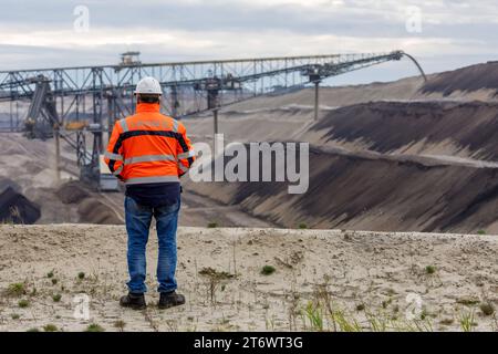 Braunkohletagebau Jaenschwalde DEU/Deutschland/Brandenburg/Jaenschwalde, 10.11.2023, Tagebau Jaenschwalde LEAG im lausitzer Revier, Ein LEAG-Mitarbeiter steht im Tagebau Jaenschwalde und blickt auf die Foerderbruecke F60 in der Grube. Der Kohleabbau im Braunkohletagebau Jaenschwalde wird voraussichtlich Ende des Jahres 2023 eingestellt und der Tagebau geschlossen. *** Jaenschwalde mine de lignite à ciel ouvert DEU Allemagne Brandenburg Jaenschwalde, 10 11 2023, Jaenschwalde mine à ciel ouvert LEAG dans la zone minière de Lausitz, Un employé de LEAG se tient dans la mine à ciel ouvert de Jaenschwalde et regarde le convoi F60 Banque D'Images