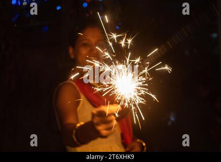 Assam, Inde. 12 novembre 2023. Femme lumière phuljhari ou allume-feu de bâton, à l'occasion du festival Diwali, la fête hindoue des lumières, à Guwahati, Assam, Inde, le 12 novembre 2023. Crédit : David Talukdar/Alamy Live News Banque D'Images