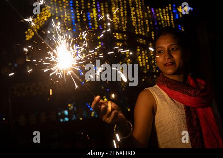 Assam, Inde. 12 novembre 2023. Femme lumière phuljhari ou allume-feu de bâton, à l'occasion du festival Diwali, la fête hindoue des lumières, à Guwahati, Assam, Inde, le 12 novembre 2023. Crédit : David Talukdar/Alamy Live News Banque D'Images