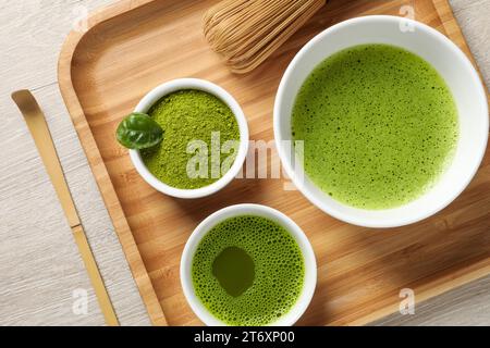 Thé matcha frais, fouet en bambou, cuillère et poudre verte sur table en bois, vue de dessus Banque D'Images