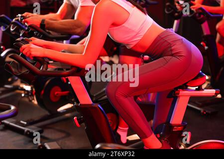 Les gens s'entraînent sur des vélos d'exercice dans le club de fitness, closeup Banque D'Images