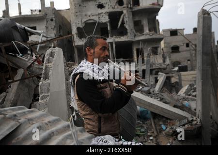 Rafah, Gaza. 12 novembre 2023. Imad Rabayaa 48, (L) joue le ney au milieu des ruines de la maison familiale détruite lors d’une frappe israélienne à Rafah, dans le sud de la bande de Gaza, le dimanche 7 novembre 2023. Robayaa dit que l'immeuble dans lequel il vivait a été détruit par un bombardement israélien le 7 octobre, le premier jour de la guerre à Gaza. Amal Rabayaa, mari d’Imad, s’infiltre maintenant avec d’autres membres de sa famille dans une école des Nations Unies à Rafah, mais rentre chez elle le matin et fait face à la lutte quotidienne pour trouver de la nourriture et de l’eau. Photo par Ismael Mohamad/UPI crédit : UPI/Alamy Live News Banque D'Images