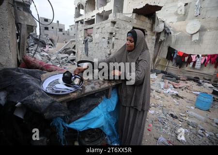 Rafah, Gaza. 12 novembre 2023. Amal al al-Robayaa 44, lave des ustensiles de cuisine au milieu des ruines de la maison familiale détruite lors d’une frappe israélienne à Rafah, dans le Sud de la bande de Gaza, le dimanche 7 novembre 2023. Robayaa dit que l'immeuble dans lequel il vivait a été détruit par un bombardement israélien le 7 octobre, le premier jour de la guerre à Gaza. Amal Rabayaa, mari d’Imad, s’infiltre maintenant avec d’autres membres de sa famille dans une école des Nations Unies à Rafah, mais rentre chez elle le matin et fait face à la lutte quotidienne pour trouver de la nourriture et de l’eau. Photo par Ismael Mohamad/UPI crédit : UPI/Alamy Live News Banque D'Images