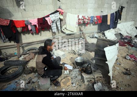 Rafah, Gaza. 12 novembre 2023. Imad Rabayaa 48, fabrique de la nourriture au milieu des ruines de la maison familiale détruite lors d’une frappe israélienne à Rafah, dans le sud de la bande de Gaza, le dimanche 7 novembre 2023. Robayaa dit que l'immeuble dans lequel il vivait a été détruit par un bombardement israélien le 7 octobre, le premier jour de la guerre à Gaza. Amal Rabayaa, mari d’Imad, s’infiltre maintenant avec d’autres membres de sa famille dans une école des Nations Unies à Rafah, mais rentre chez elle le matin et fait face à la lutte quotidienne pour trouver de la nourriture et de l’eau. Photo par Ismael Mohamad/UPI crédit : UPI/Alamy Live News Banque D'Images