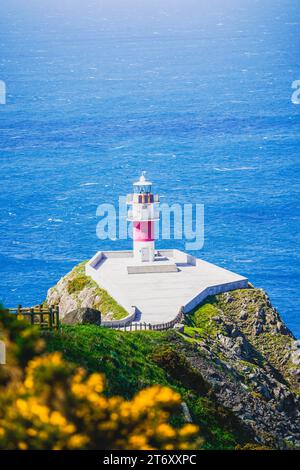 Un majestueux phare blanc est situé au sommet d'une colline pittoresque surplombant une vaste étendue d'océan bleu Banque D'Images