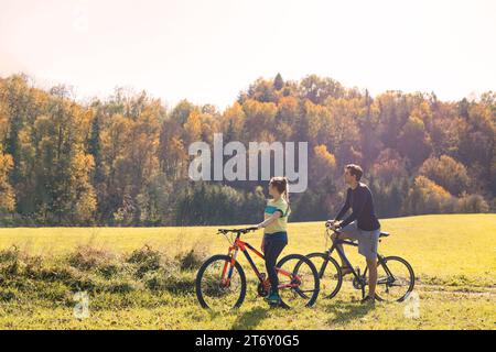 Jeune couple souriant et détendu profitant d'une balade à vélo dans une belle campagne. Concept actif de vacances d'automne. Banque D'Images