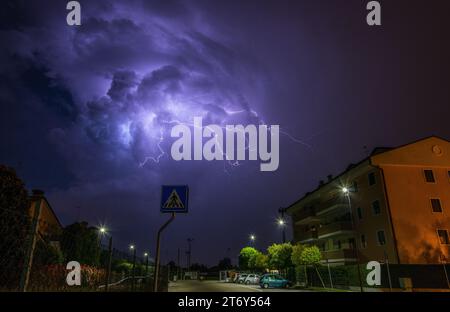 Plusieurs branches de foudre de l'énorme thunderhead surplombant les condos et les maisons de la ville. Orage d'été avec des éclairs ramifiés. Banque D'Images