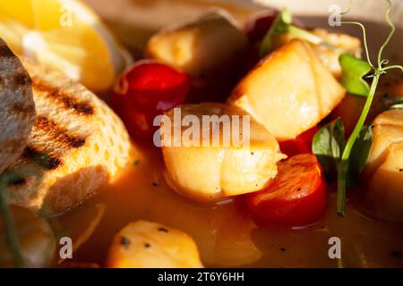 Coquilles Saint-Jacques portugaises frites dans une sauce au vin blanc avec citron, tomates et pain grillé. Fruits de mer, régime méditerranéen. Banque D'Images