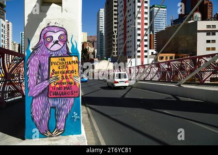 La Paz, Bolivie, 7 juillet 2022 : un minibus passe devant une fresque sur un pilier du Puente Gemelo / Twin Bridge d'un paresseux protestant contre les chaqueos / les incendies ont commencé délibérément à nettoyer les forêts tropicales de Chiquitania et les régions amazoniennes des basses terres boliviennes. La déforestation est devenue un énorme problème en Bolivie au cours de la dernière décennie en particulier ; en 2022, Global Forest Watch a placé la Bolivie au troisième rang mondial pour la perte de forêts primaires. Une grande partie de la déforestation est la politique du gouvernement d'étendre la frontière agricole du pays pour produire du soja et du bétail pour l'exportation vers la Chine en particulier. Banque D'Images