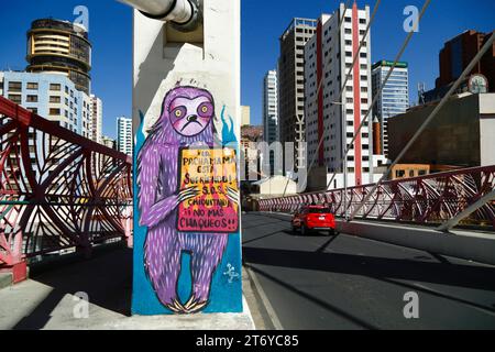 La Paz, Bolivie, 7 juillet 2022 : une voiture rouge passe devant une fresque sur un pilier du Puente Gemelo / Twin Bridge d'un paresseux protestant contre les chaqueos / les incendies ont commencé délibérément à nettoyer les forêts tropicales de Chiquitania et les régions amazoniennes des basses terres boliviennes. La déforestation est devenue un énorme problème en Bolivie au cours de la dernière décennie en particulier ; en 2022, Global Forest Watch a placé la Bolivie au troisième rang mondial pour la perte de forêts primaires. Une grande partie de la déforestation est la politique du gouvernement d'étendre la frontière agricole du pays pour produire du soja et du bétail pour l'exportation vers la Chine en particulier. Banque D'Images