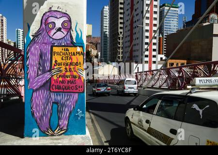 La Paz, Bolivie, 7 juillet 2022 : un taxi passe devant une fresque sur un pilier du Puente Gemelo / Twin Bridge d'un paresseux protestant contre les chaqueos / les incendies ont commencé délibérément à nettoyer les forêts tropicales de Chiquitania et les régions amazoniennes des basses terres boliviennes. La déforestation est devenue un énorme problème en Bolivie au cours de la dernière décennie en particulier ; en 2022, Global Forest Watch a placé la Bolivie au troisième rang mondial pour la perte de forêts primaires. Une grande partie de la déforestation est la politique du gouvernement d'étendre la frontière agricole du pays pour produire du soja et du bétail pour l'exportation vers la Chine en particulier. Banque D'Images