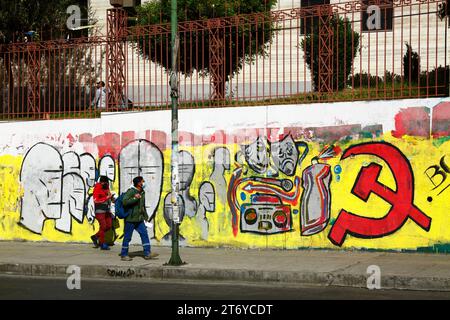 Des hommes passent devant une fresque du Parti communiste bolivien près de la principale université de l'UMSA dans le centre de la Paz, en Bolivie Banque D'Images