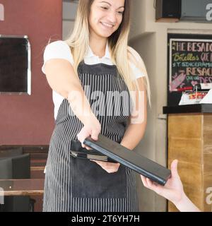 Serveuse souriante donnant le menu au client restaurant Banque D'Images
