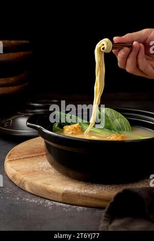 Bol noir avec assiette en bois de soupe de nouilles Banque D'Images