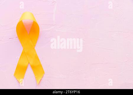 Ruban jaune de couleur symbolique sarcome os cancer fond rose Banque D'Images