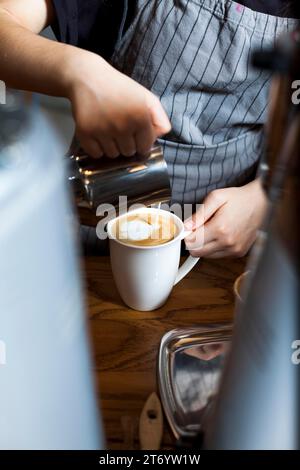 Barista professionnel qui verse du café latte mousse Banque D'Images