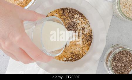 Femme préparant le petit déjeuner. Flocons d'avoine à base d'avoine entière, de farine de lin, de graines de Chia et de lait. Vue rapprochée du dessus Banque D'Images