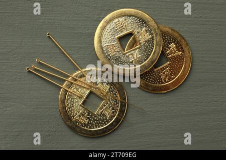 Aiguilles d'acupuncture et pièces chinoises antiques sur table en bois gris, pose plate Banque D'Images