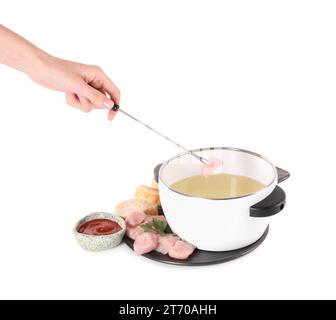 Femme trempant morceau de viande crue dans l'huile dans un pot à fondue sur fond blanc Banque D'Images