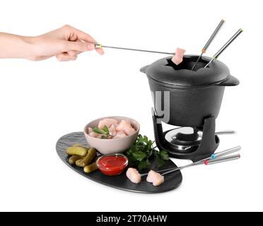 Femme trempant morceau de viande crue dans l'huile dans un pot à fondue sur fond blanc Banque D'Images