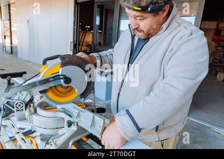 En travaillant sur l'outil de découpe de scie à découper, l'ouvrier découpe les moulures en bois de base Banque D'Images