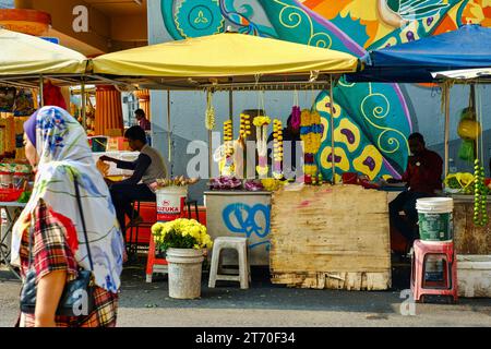 Kuala Lumpur, Malaisie - 18 octobre 2023 : Femme en hijab marchant devant des vendeurs de guirlandes de fleurs au temple Sri Mahamariamman dans Chinatown, près de Petaling St Banque D'Images