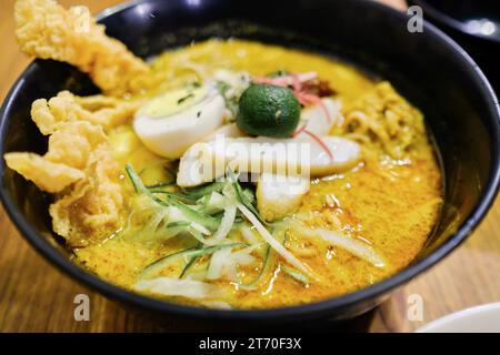 Un bol de Nyonya laksa avec vermicelles de riz, poulet râpé, caillé de haricots frits, œuf dur, concombre julien, germe de haricot, boulettes de poisson à Limapulo Banque D'Images