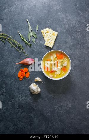 Soupe de nouilles au poulet dans un bol sur fond noir avec des légumes Banque D'Images