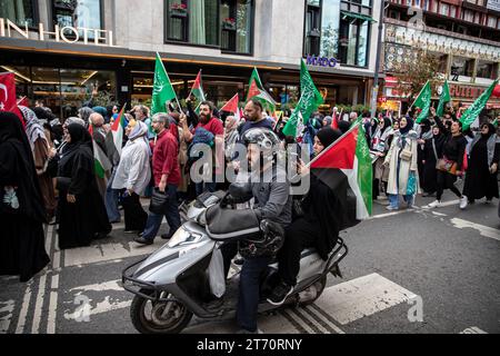 Le passager derrière le motocycliste passant devant les manifestants marchant vers Sultanahmet avec des drapeaux palestiniens les a également soutenus avec le drapeau palestinien. Palestine Initiative Platform a formé une chaîne humaine d'Edirnekapi à Sultanahmet pour protester contre les attaques israéliennes sur Gaza. (Photo Onur Dogman / SOPA Images/Sipa USA) Banque D'Images