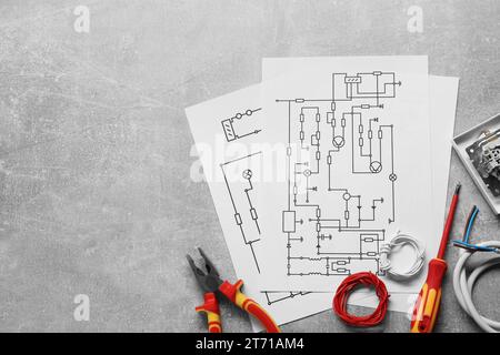 Schémas de câblage, fils et outils sur table grise, à plat. Espace pour le texte Banque D'Images