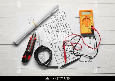 Schémas de câblage, fils et multimètre numérique sur table en bois blanc, pose à plat Banque D'Images