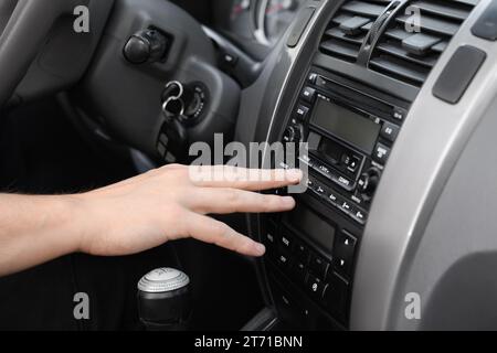 Sélection de la radio favorite. Femme appuyant sur le bouton sur l'audio du véhicule dans la voiture, gros plan Banque D'Images